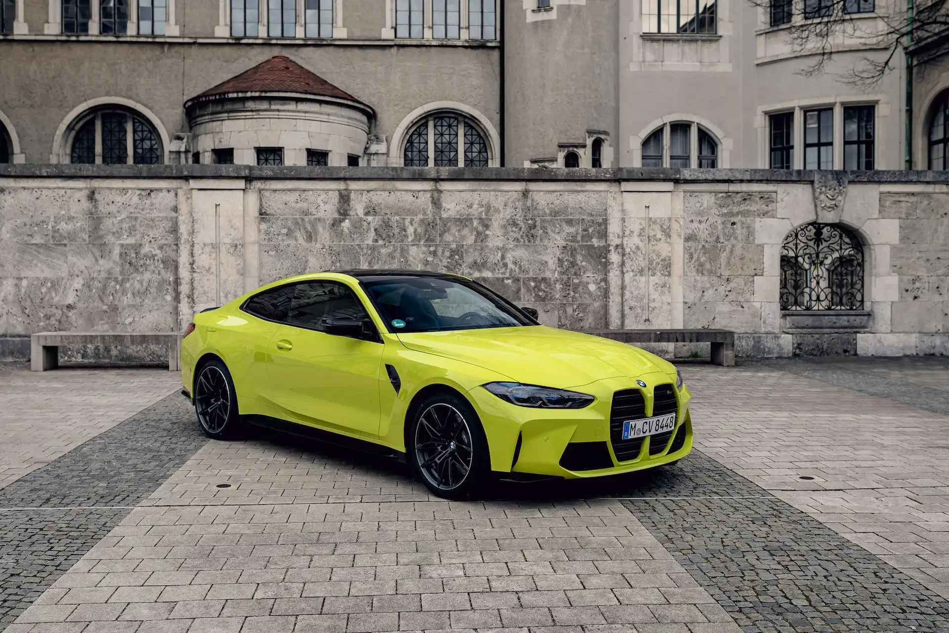 Ein gelber BMW M4 Competition steht schräg vor dem Bayrischen Nationalmuseum.